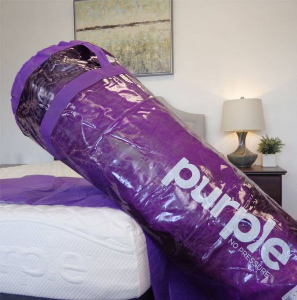 wrapped purple mattress leaning on bed