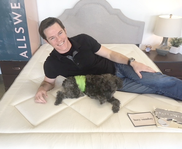guy and dog laying on allswell luxe hybrid mattress aerial view 